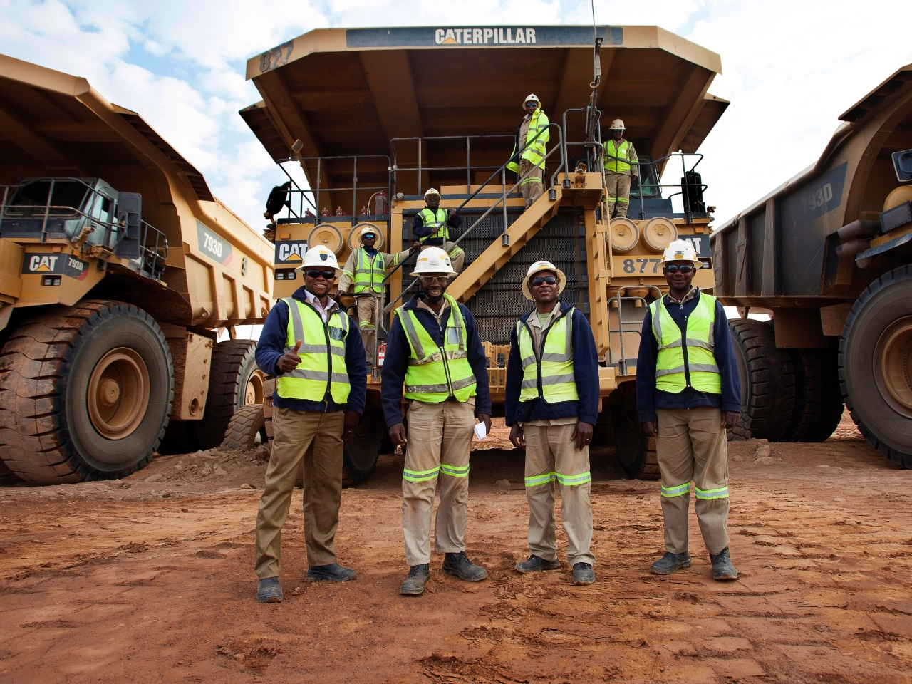 Mining team standing beside heavy mining equipment